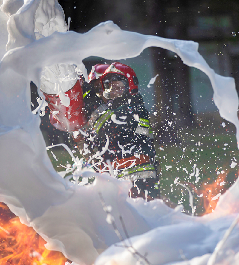 a firefighter using foam to put out a fire